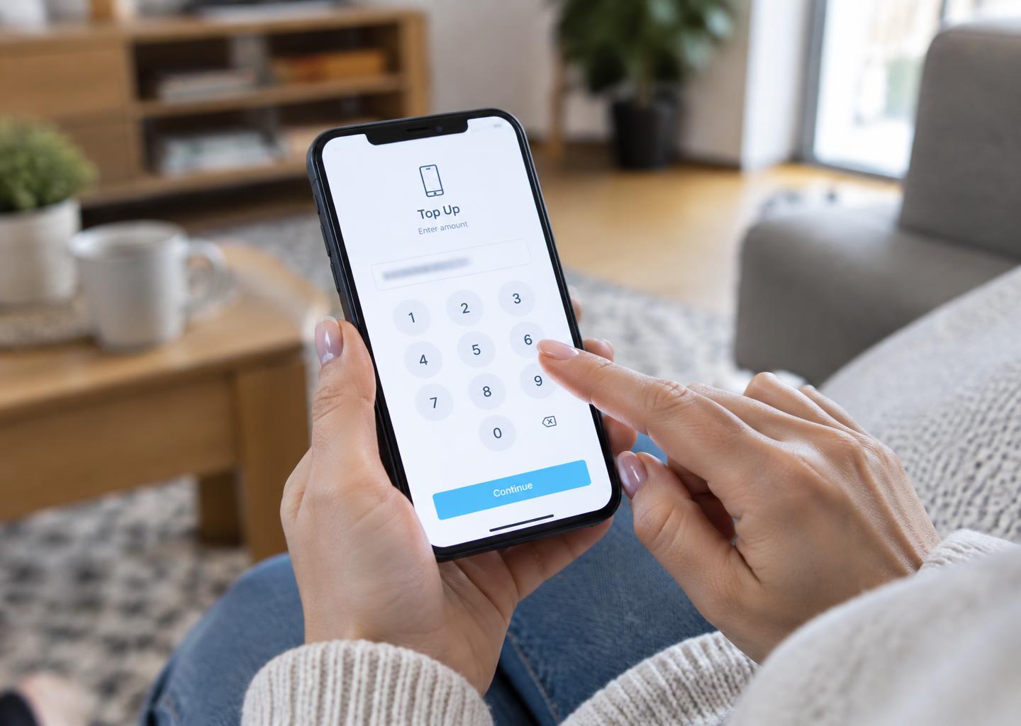 Customer entering a mobile number on a smartphone recharge screen at home